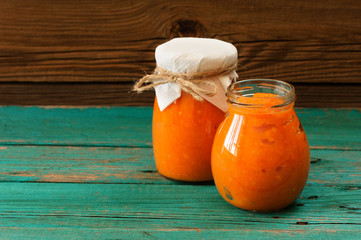 Homemade sweet pumpkin jam in two glass jars with napkin and rop