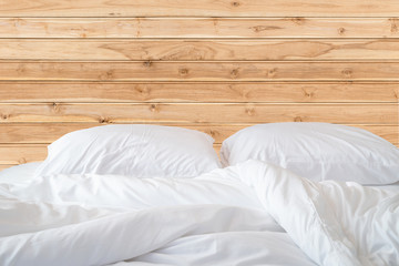 White bedding sheets and pillow on wooden wall room background,