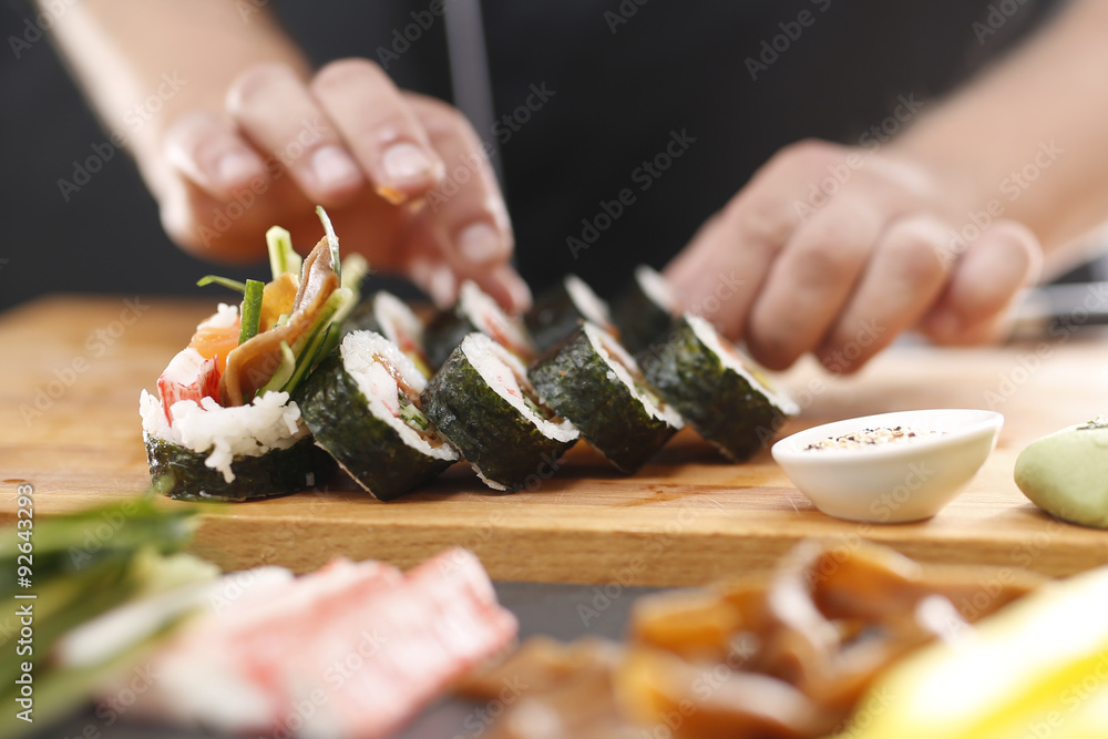 Sushi master przyrządza futomaki z łososiem, krewetką i ogórkiem - obrazy, fototapety, plakaty 