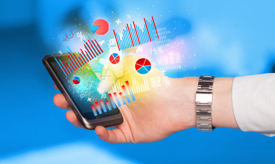Business man holding smartphone with chart symbols