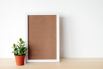 Blank white wooden frame and tree on wood board over white wall