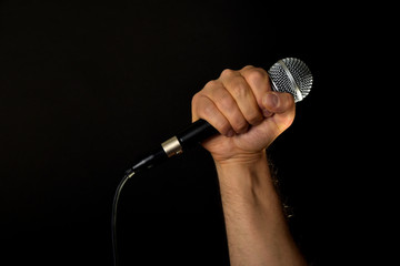 Male hand with microphone isolated on black