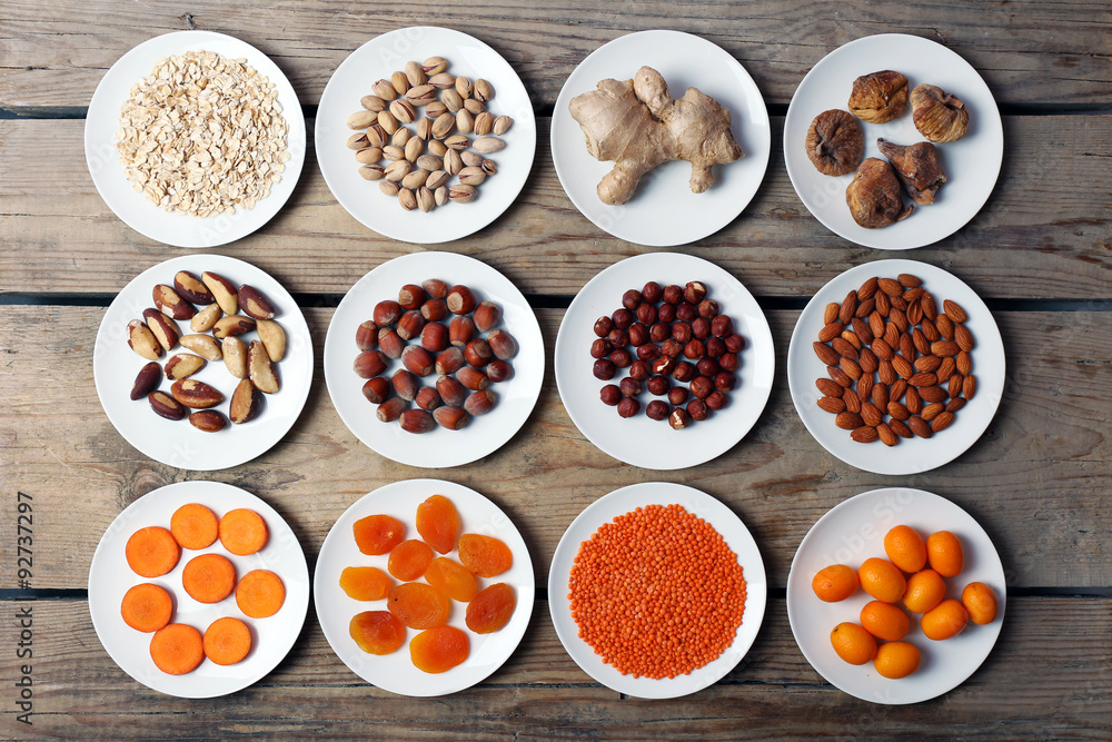 Different products on saucers on wooden table, top view