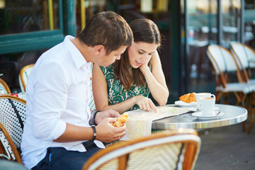 Wall Mural - Young romantic couple with map in French cafe