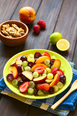 Wall Mural - Fresh fruit salad of grape, strawberry, plum and nectarine served on plate, photographed on dark wood with natural light (Selective Focus, Focus in middle of salad)