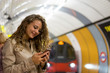 A woman using a mobile phone on the tube underground station, Lo