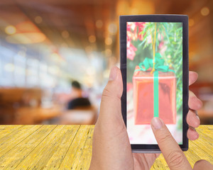 Wall Mural - male hand is holding a modern touch screen phone and Coffee shop