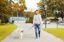 Happy Man With Labrador Dog Walking In City Park