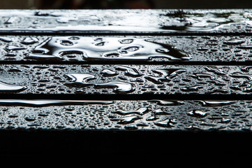 the water drops on wooden garden table, center focus for background.
