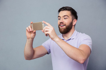 Wall Mural - Smiling man making photo on smartphone