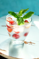 Canvas Print - Glass of cold refreshing summer drink with berries and ice cubes on table close up