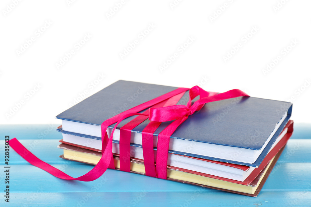Stack of books with ribbon on table isolated on white