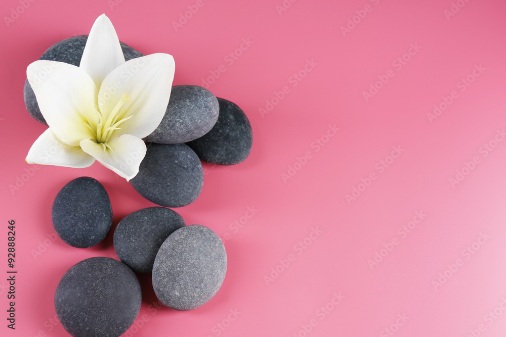 Spa stones with flower on pink background