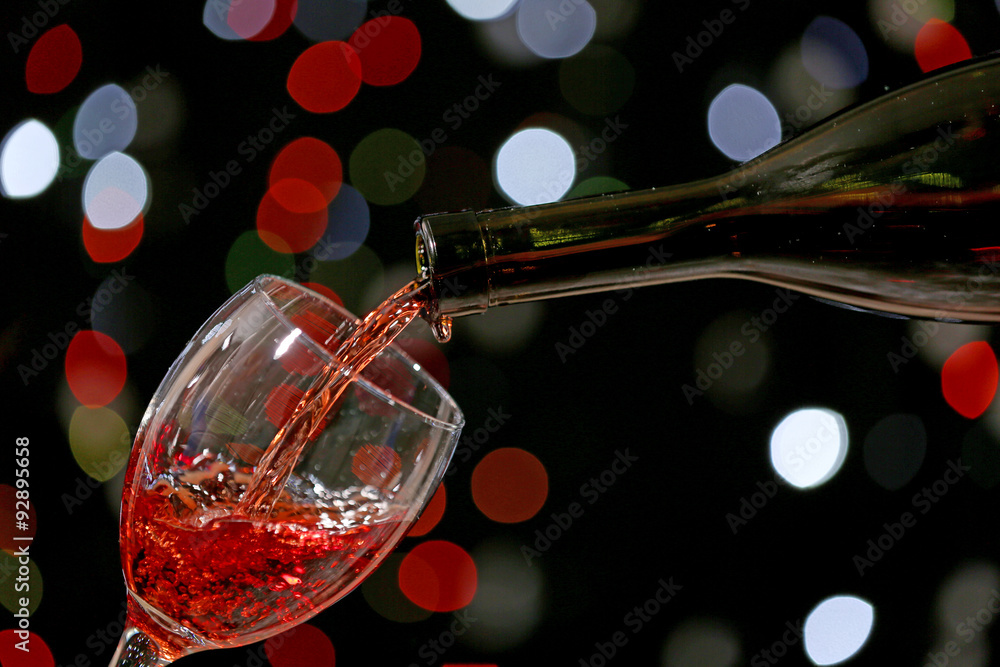 Wine pouring in glass on bright background
