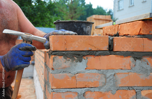 Bricklayer Using A Bricklaying Hammer To Build New Red Brick Wall Bricklayer Using A Bricklaying Hammer To Build New Red Brick Wall Outdoor Basics Masonry