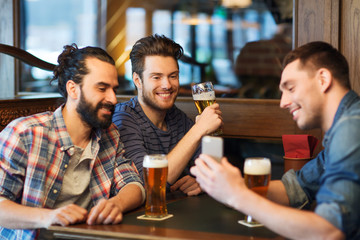 Wall Mural - male friends with smartphone drinking beer at bar