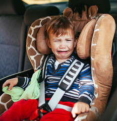 Crying baby boy in car seat.