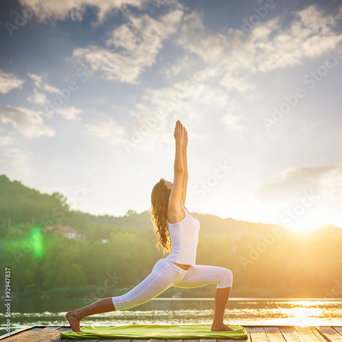 Fotografia Woman doing yoga on the lake - beautiful lights
