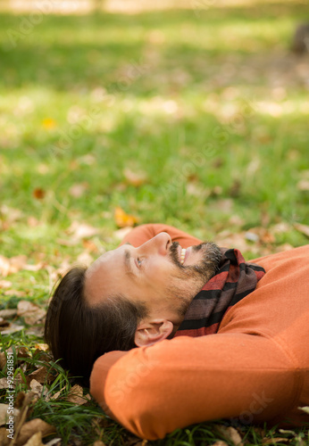 Fotografija Handsome middle-aged man lying on the autumn leaves in park