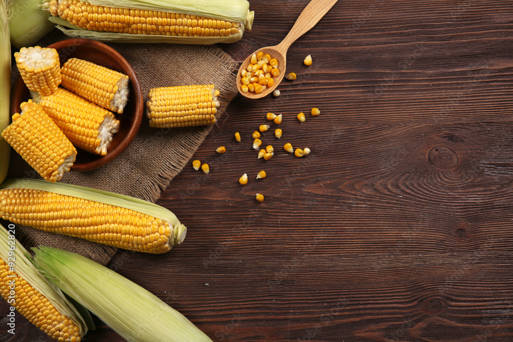 Ripe corn on sacking on wooden background