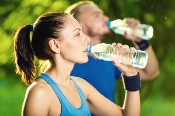 Man and woman drinking water from bottle after fitness sport