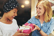 © Flamingo Images - Young woman giving a friend a surprise gift