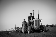 Farmer In Old-fashioned Tractor Sowing Crops At Field, Black And White
