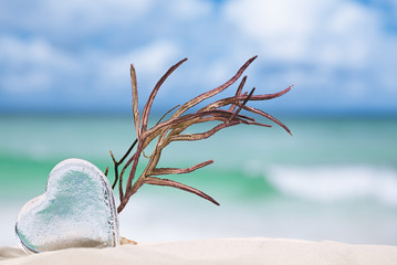 clear glass heart on white sand beach