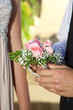 Close up of a teenage prom couple outside. The boy is giving his date a rose wrist corsage