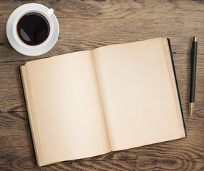 Wall Mural - Open book with pen and coffee cup on old wooden table