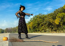 Halloween Theme Dressed Lady Hitchhiking On Paved Road Witch In Black Dress Hat And High Heels Boots Run Out Of Fuel For Her Broom And Trying To Catch Up Another Mode Of Transportation