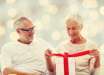 Poster - happy senior couple with gift box at home