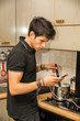 © theartofphoto - Young Man with Cell Phone Cooking Food on Stove