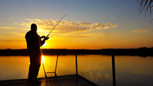 Young Man Fishing On A Lake At Sunset