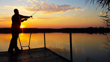 Young Man Fishing On A Lake At Sunset
