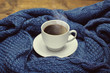 Cup of coffee on the warm blue knitted sweater background. Toned style instagram filters