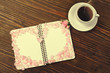 Open notebook and cup of hot coffee on wooden table. Romantic decor from roses petals.Toned style instagram filters