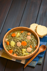 Wall Mural - Lentil soup made with potato, carrot, onion and sausage slices, photographed on dark wood with natural light (Selective Focus, Focus on the middle of the soup)