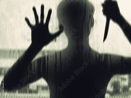 Fotografia Shadowy figure with a knife behind glass,soft focus