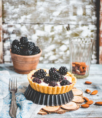 tartlets with cream cheese and blackberry on a light wooden.tabl