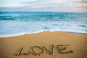 travel concept - word love written in sand on the beach