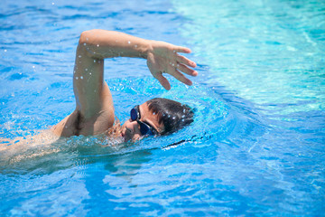 Wall Mural - Young man swimming the front crawl/freestyle in a pool