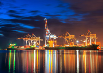 Wall Mural - Container Cargo freight ship with working crane bridge in shipyard at dusk.