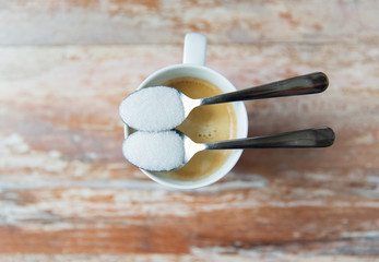 close up of white sugar on teaspoon and coffee cup