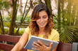 © pablocalvog - Smiling lady using tablet ahead palms park