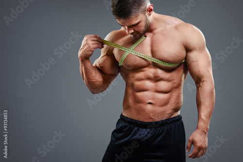 Plakat Pracowniany portret mięśniowy sporta mężczyzna pomiarowa klatka piersiowa z taśmy miarą odizolowywającą nad popielatym tłem. Koncepcja wzmocnienia klatki piersiowej Bodybuilder.