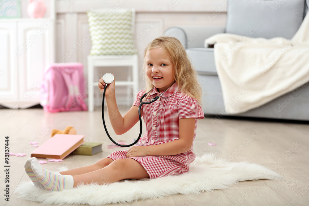 Little girl playing with stethoscope in the room