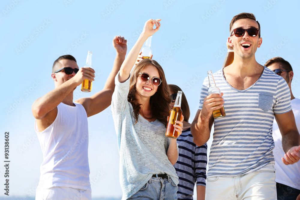Young people with beer on the riverside