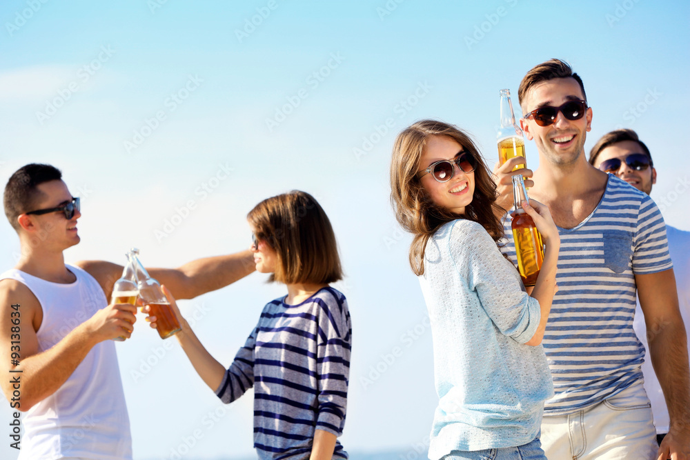 Young people with beer on the riverside