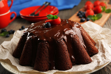 Wall Mural - Delicious chocolate cake with berries in plate on table, closeup